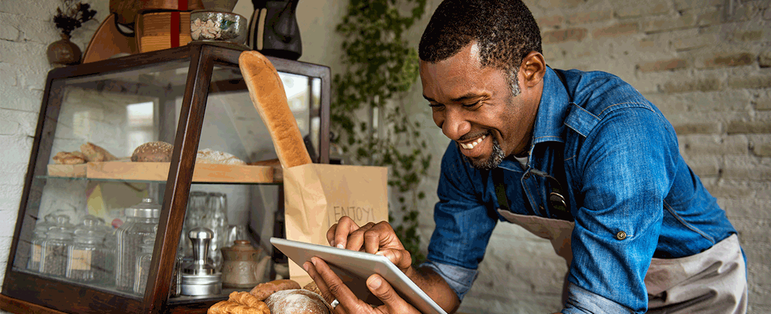 Cafe worker smiling and using an ipad.
