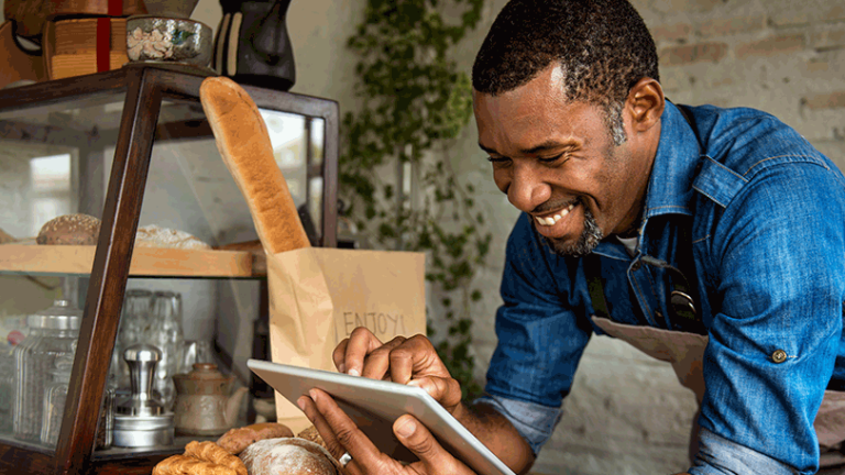 Cafe worker smiling and using an ipad.