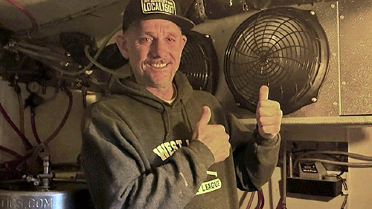 Smiling man in front of refrigeration system component.