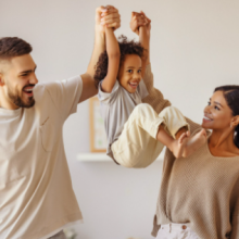 mom and dad swinging child by arms