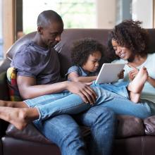 Two adults and a child laying comfortably on a couch