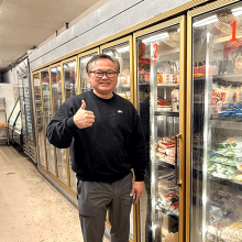 Man standing in front of the refrigerator with food and beverages.